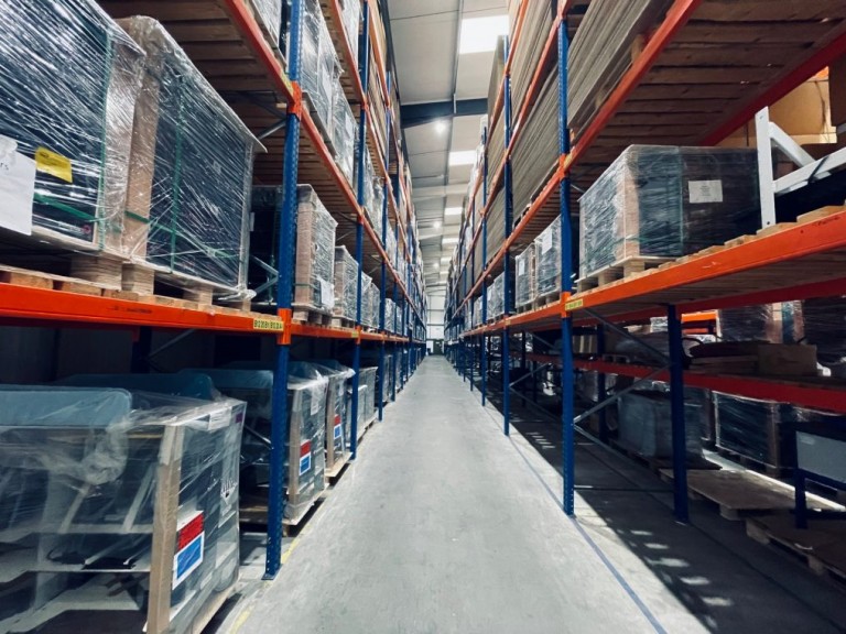 Warehouse aisle with tall storage racks and wrapped pallets on both sides