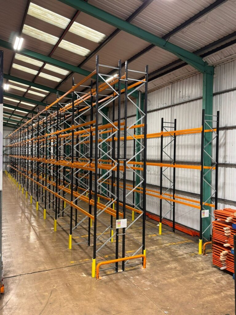 New pallet racking installed in a warehouse with orange beams and black uprights