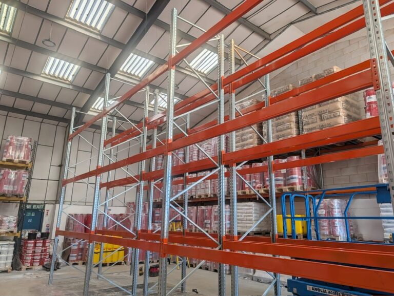 New Dexion warehouse racking being installed with orange beams and pallets stored behind
