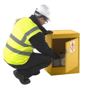 Worker in hi vis jacket opening yellow hazardous storage cupboard with chemical containers